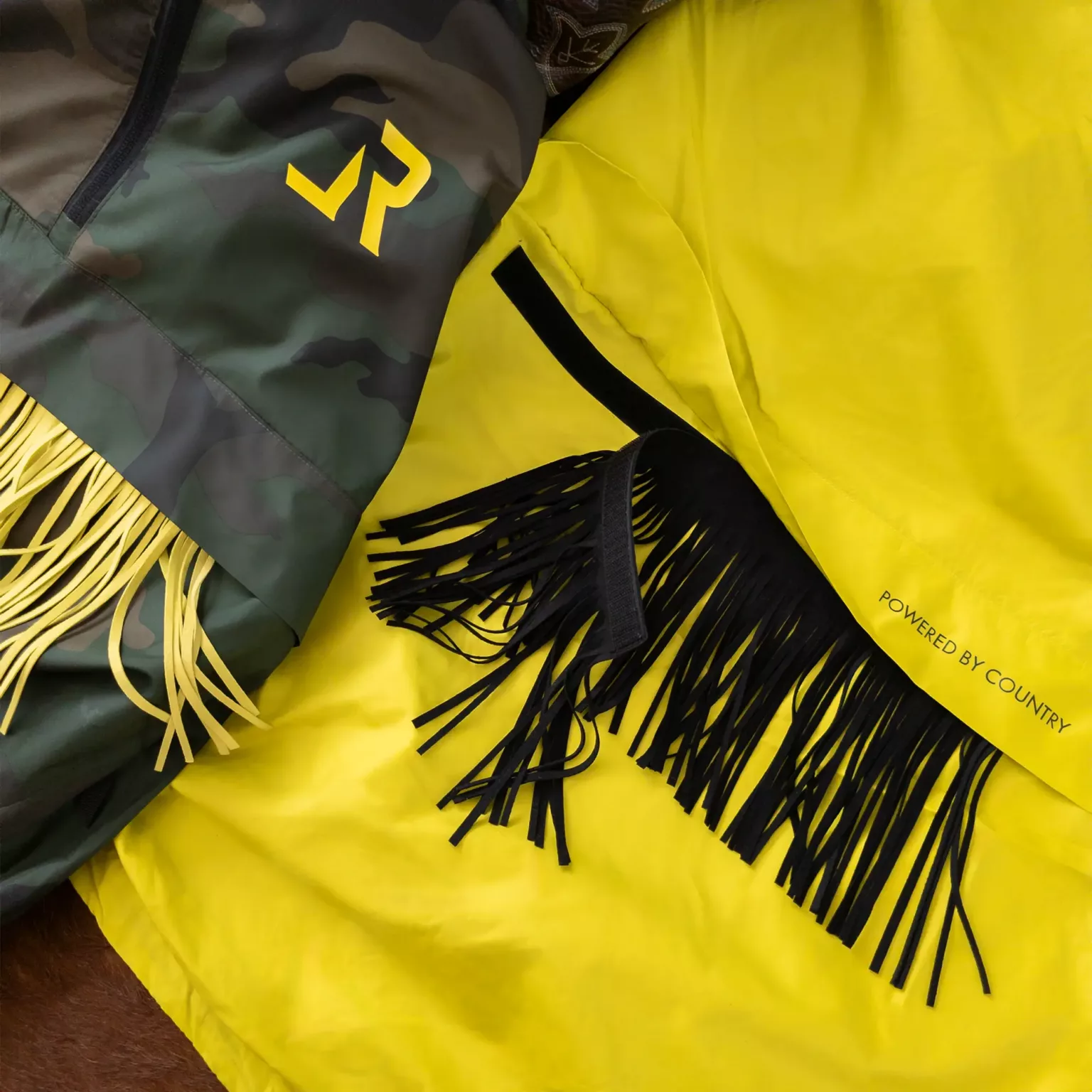 LavendersRanch Windbreaker Jacket camouflage with yellow fringe tazzels, shown next to the citrus windbreaker version with black tazzels showcasing the removability functionality of the fringes.