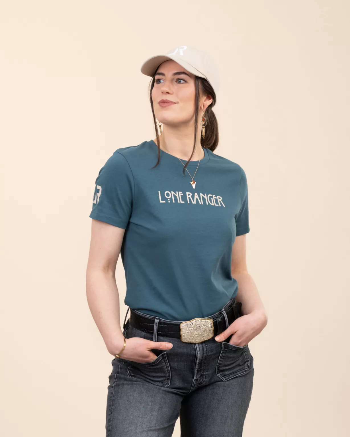 Woman wearing the teal women’s t-shirt by LavendersRanch (LR) with beige Lone Ranger print on the chest and LR logo on the sleeve, made from organic cotton.
