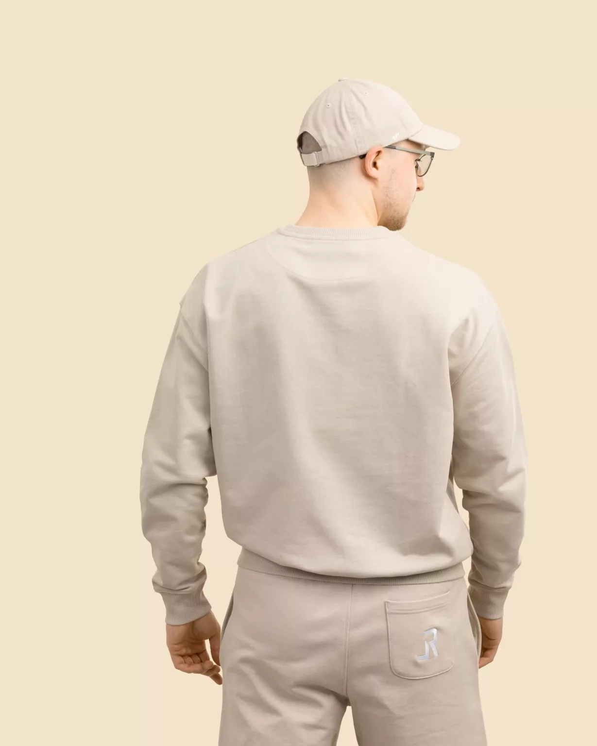 Back view of a man wearing the desert beige Original unisex sweatshirt by LavendersRanch (LR), sustainable western country style made from organic cotton.