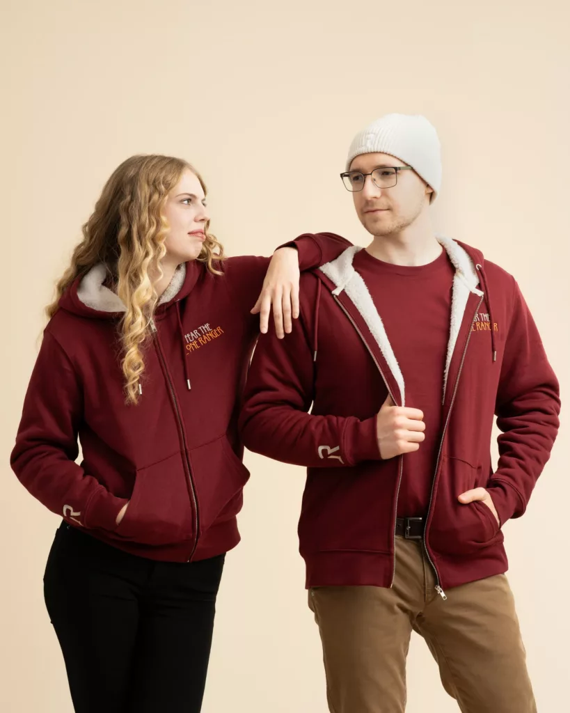 Man and woman wearing burgundy sustainable hoodie jackets from LavendersRanch (LR), showcasing the unisex fit. Both jackets feature the cozy, fully lined interior and "Fear the Lone Ranger" embroidery.