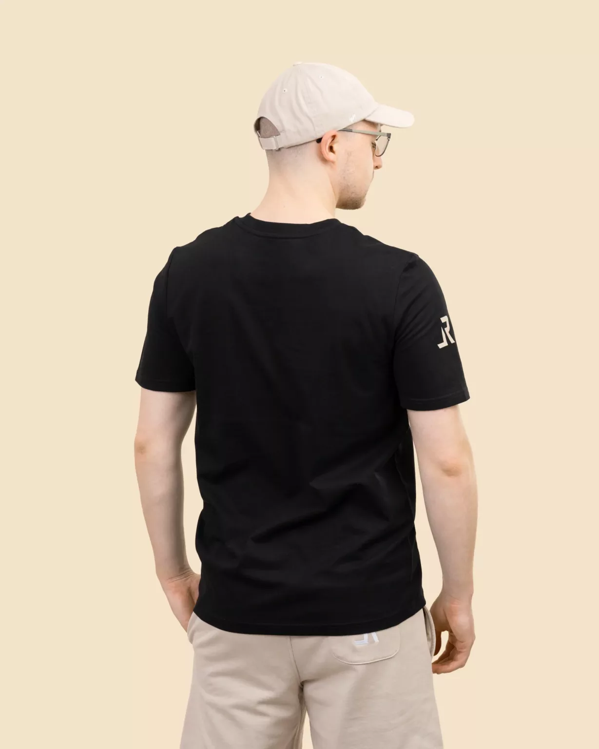 Back view of a male model wearing a black unisex t-shirt by LavendersRanch made from GOTS certified organic cotton.
